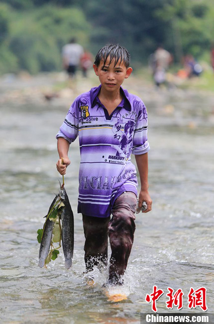 圖為7月9日，一名男孩在鬧魚(yú)節(jié)活動(dòng)中抓到了兩條魚(yú)。譚凱興 攝