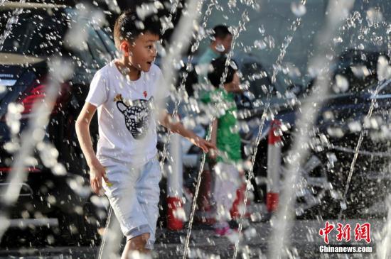 山西太原最高溫36℃,兒童在噴泉周圍戲水消暑。