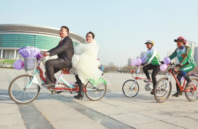 氣球和鮮花裝點(diǎn)的雙人自行車，新郎郝幸福載著美麗新娘回家。