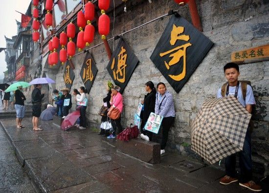 　4月29日上午11時20分，一些游客和古城當(dāng)?shù)氐木用穸阍谝粋€酒吧的屋檐下避雨。這些當(dāng)?shù)鼐用褚詾橛慰团恼罩\生，一場降雨讓他們的生意更加清淡。