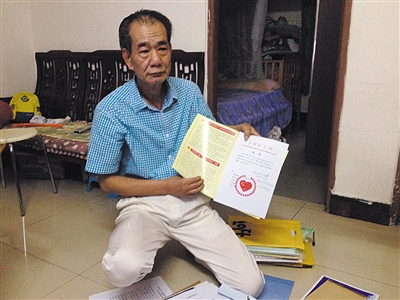 翻出一家網(wǎng)站贈予的“中國好人”證書，區(qū)少坤單膝跪在地上，“你看，我是中國好人啊?！?范春旭 攝