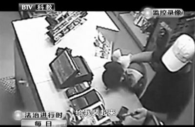 戴帽男子一手掐住加油站營業(yè)員，一手持發(fā)令槍指向另一營業(yè)員，要求“把錢給我裝起來”。