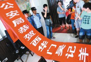 面對(duì)警方收繳的條幅，老板楊某也不好意思地用手遮擋臉