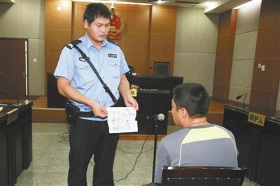 昨日庭審中，法警向趙某出示其扎完車胎后所留辱罵公司的紙條。通訊員 李秀文 攝