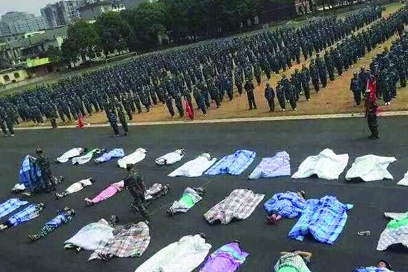 20多名女生躺在瀝青跑道上，身上嚴嚴實實地裹著棉被，接受太陽的照曬。
