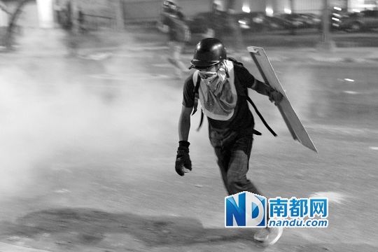 反政府示威者在與警察的沖突中躲避催淚彈。