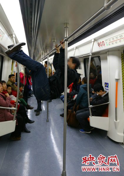 地鐵試乘日，一男子在車廂內(nèi)攀爬扶手自?shī)首詷?lè)
