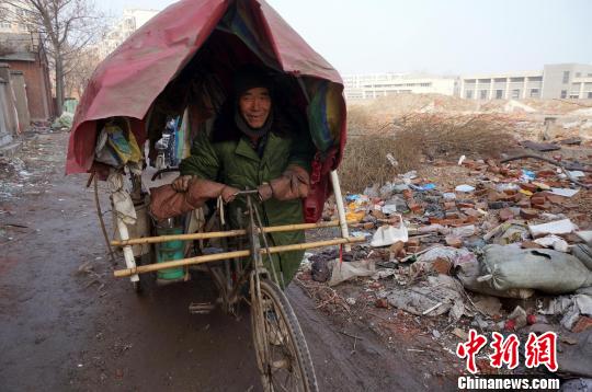 圖為老人走出窩棚，推著三輪車(chē)準(zhǔn)備出去撿拾廢品。周小云 攝