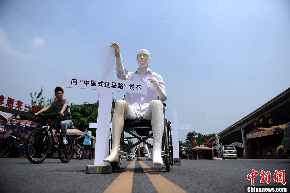 4月16日，重慶市洋人街上擺放著兩個(gè)受了傷的塑料人像“模特”，旁邊十字架上寫(xiě)著向“中國(guó)式過(guò)馬路”說(shuō)不