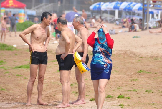 2013年7月3日，山東青島青島高溫來襲，“青島大媽”不懼滸苔，戴著“強盜面具”出現(xiàn)在海水浴場消暑降