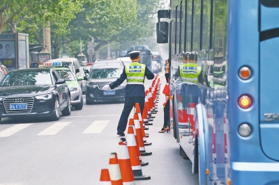 省人民醫(yī)院南門(mén)的路中間擺放反光錐，交警示意由西向東車(chē)輛從前方繞行。