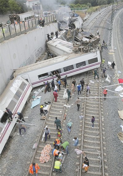 24日，救援人員在西班牙列車脫軌現(xiàn)場(chǎng)。一節(jié)車廂被強(qiáng)大的慣性拋上鐵道邊的高臺(tái)。