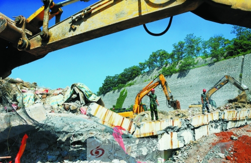 為確保道路盡早通車，工人師傅冒著烈日，指揮施工機械清理爆破現(xiàn)場