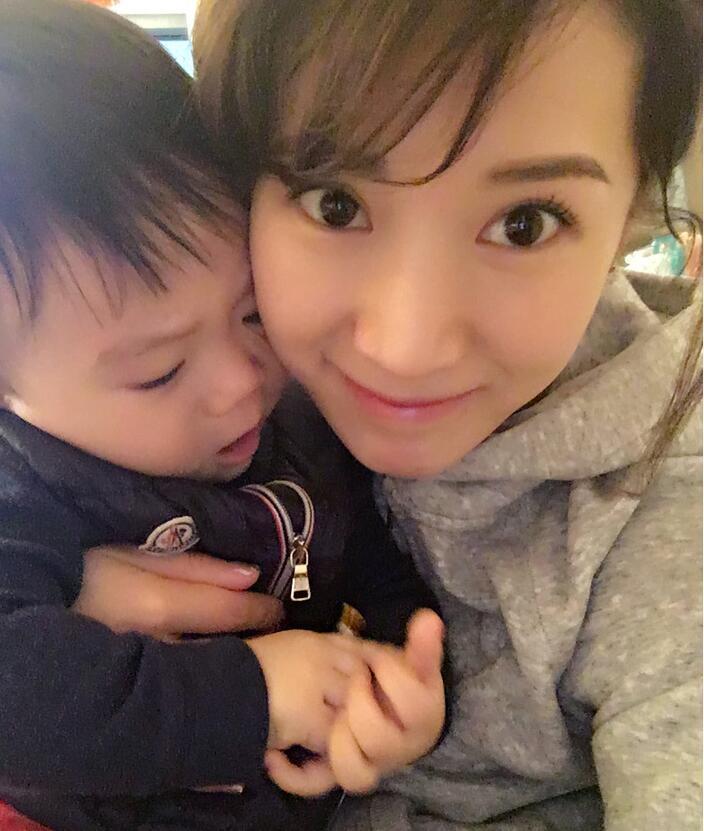 照片中李念狂吻兒子，小寶貝自顧自地玩著。