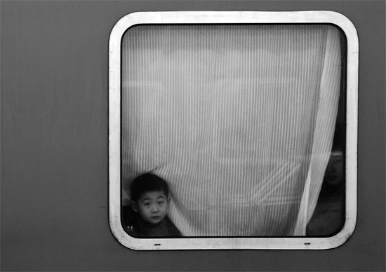 一個孩子把頭伸向窗外，他想再看送別的親人一眼