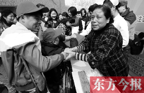 昨日，鄭大四附院的大樓前，“面人鄭”鄭玉芬（右）向前來捐款的殘疾人表示感謝