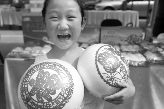 在2013河南食品安全宣傳周活動現(xiàn)場，一個小女孩抱著參展的特色大饅頭樂開了花