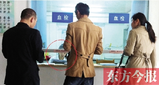 昨日，鄭州市二七區(qū)疾控中心辦證大廳，血檢窗口內(nèi)一名女工作人員，邊接受辦證者咨詢邊看報紙