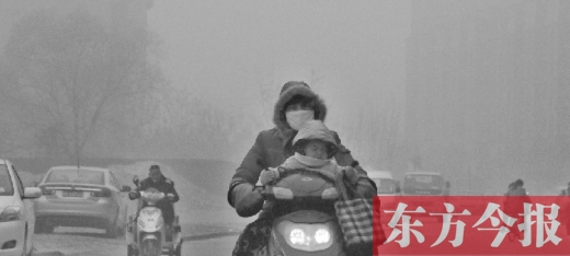 12月8日，鄭州市未來路上，一位市民帶著孩子在霧中騎行