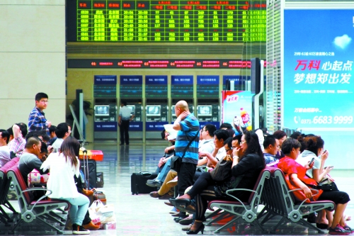 候車大廳溫度很高，一名乘客一手扇風、一手擦汗