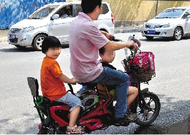 周先生騎著一輛低矮的電動(dòng)車帶著一對(duì)兒女，很不安全。