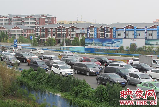 記者看到鄭州機(jī)場(chǎng)收費(fèi)站口車輛排隊(duì)，與此形成鮮明對(duì)比的是，路的對(duì)面（另一半幅）卻車輛較少，通行順暢。