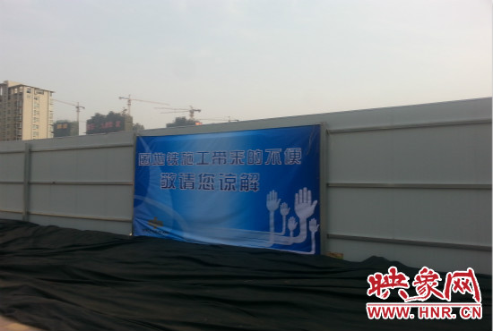 道路南側圍起了白色的圍擋，墻上標示著“因地鐵施工帶來的不便敬請您諒解”的提示牌。