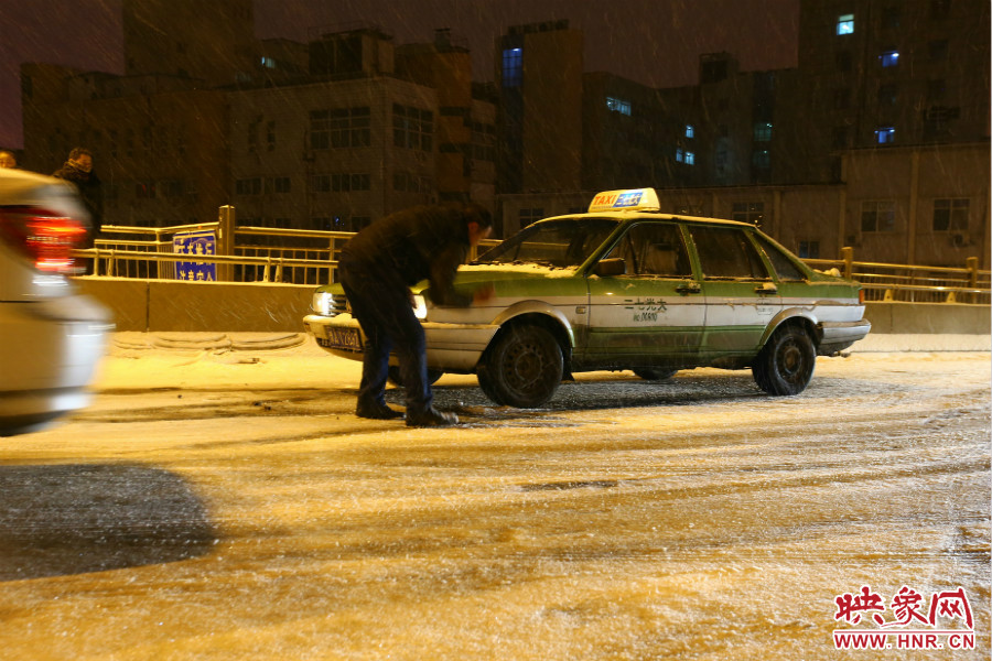 一位出租車司機(jī)在車輪前灑上雪，希望能增加輪胎的摩擦力。