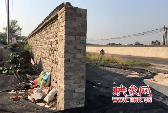 一墻之隔，一邊是道路，一邊是垃圾和荒草，市民質(zhì)疑其為遮羞墻。