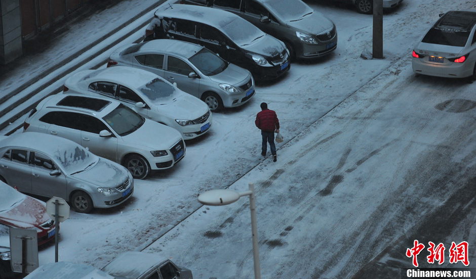 11月18日，行人在沈陽街頭的積雪中穿行。