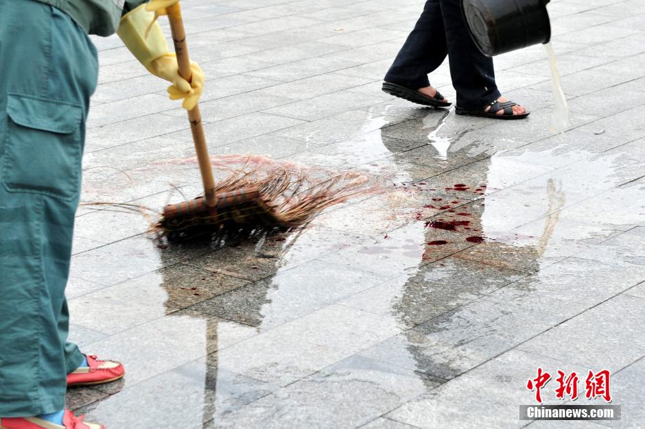 圖為環(huán)衛(wèi)工人在清理案發(fā)地點的血跡。