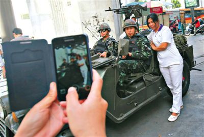 20日，泰國首都曼谷，一名婦女與執(zhí)行軍管任務的士兵合影。