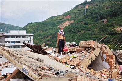 8月9日,龍頭山鎮(zhèn),一位老者在自家房屋廢墟上尋找家當(dāng)。