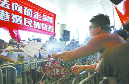 17日，在香港立法會外，一名反對政改的男子向支持派人群投擲標(biāo)牌。