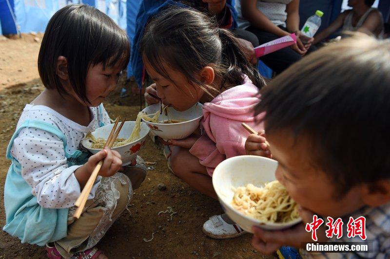 2014年8月6日，云南魯?shù)辇堫^山災(zāi)區(qū)，兒童在帳篷外吃飯。