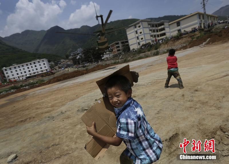 云南省昭通市魯?shù)榭h發(fā)生6.5級地震。幾個孩子在直升機降落的平地上玩耍。