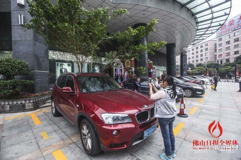 一輛停在停車位上的寶馬轎車，被墜落的樹枝砸中，樹枝徑直插入車內，現場引發(fā)不少市民圍觀拍照。
