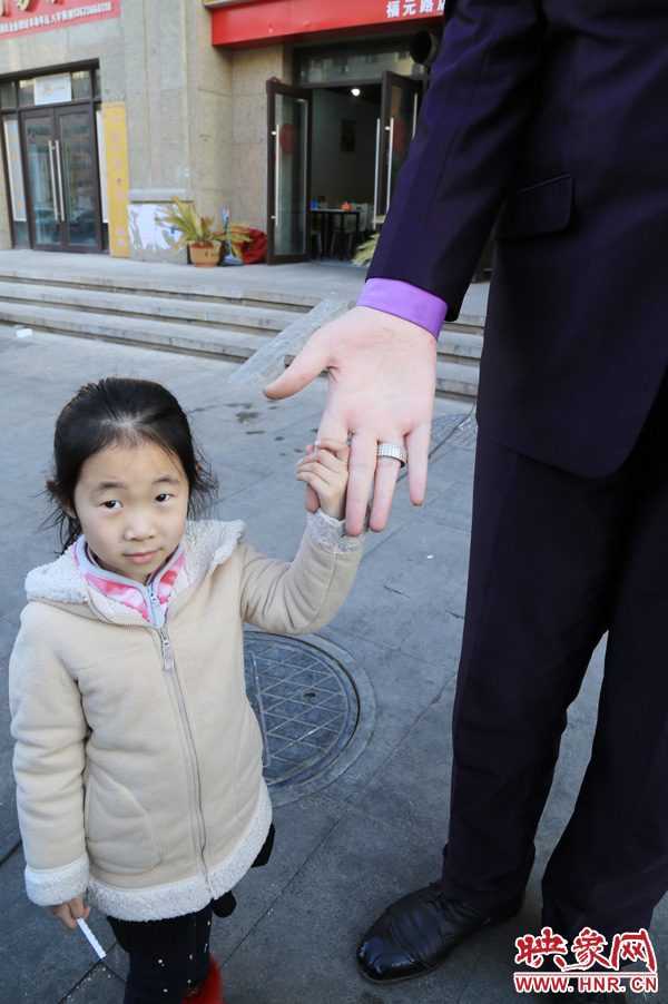 巨人“張歡”牽著一名漂亮的小女孩，兩人的手大小對(duì)比非常明顯。