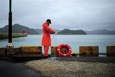 7月6日，韓國珍島，一名海岸警察在港口系救生圈。4月，客輪在珍島近海發(fā)生沉船事故后，仍有11人下落不明。