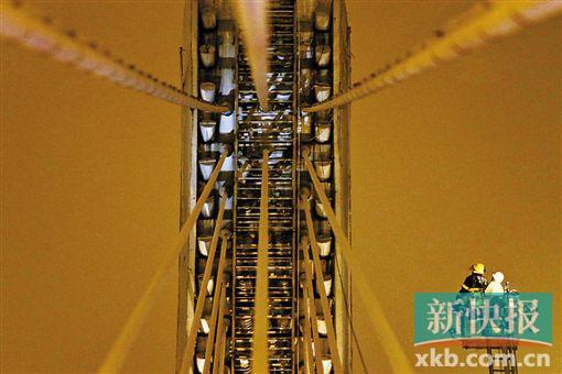 截至今日零時(shí)，男子仍未有下橋舉動(dòng)。圖為公安和消防人員乘消防云梯在高空上和男子交談。