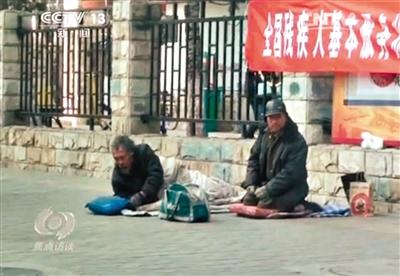 工人體育場北路，兩位乞討者路邊乞討，并輪流扮成“病人”（躺地者）。 央視截圖