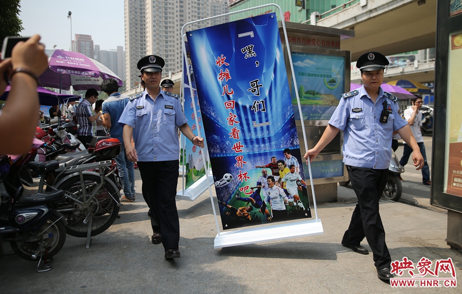 7月2日上午，鄭州市紫荊山地鐵站出入口，執(zhí)法人員抬著寫有勸導(dǎo)語的宣傳板，前往占道經(jīng)營攤位“圍觀執(zhí)法”